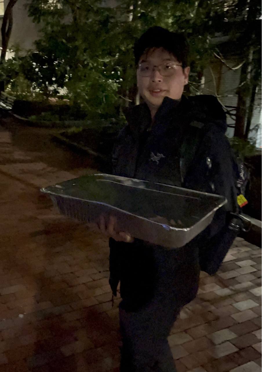 Jack in the rain, holding a catering tray — a hacker house food run