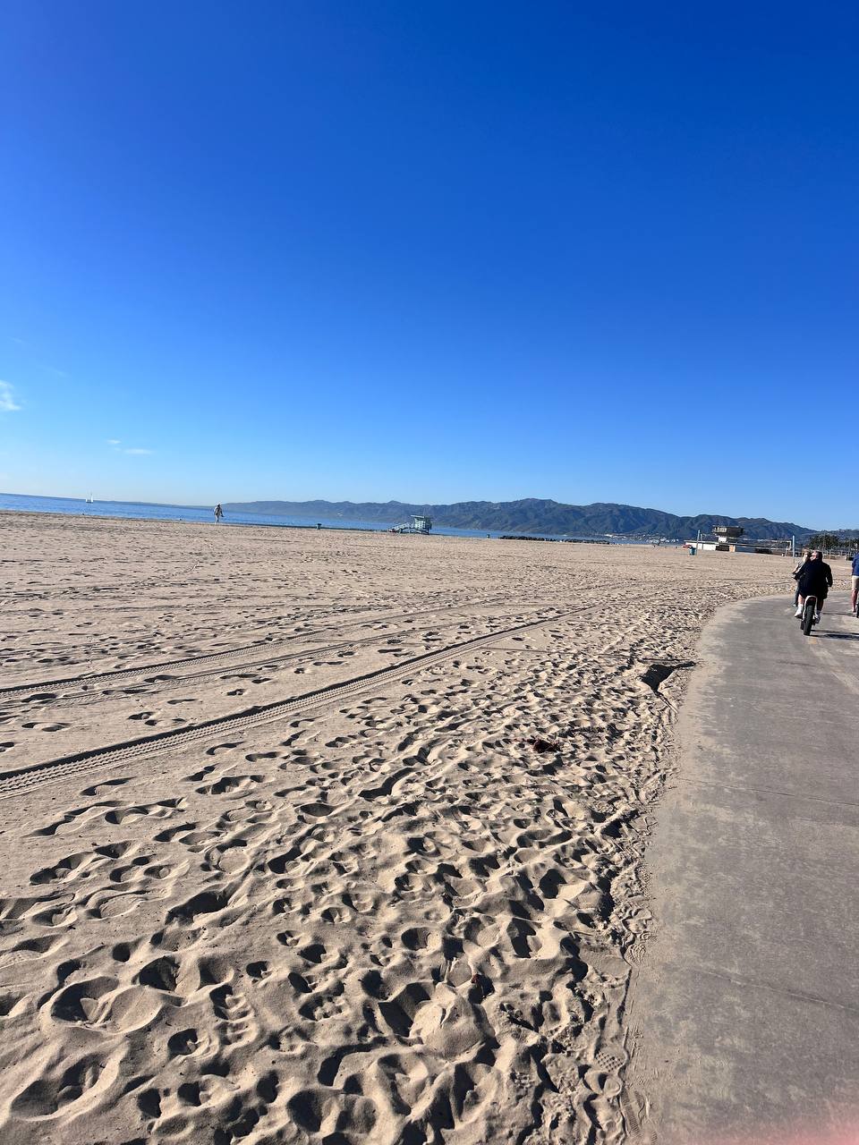 Santa Monica beach — wide sandy shore, bike path, Santa Monica mountains in the distance
